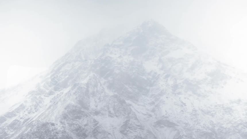 Snow falls rapidly atop a mountain