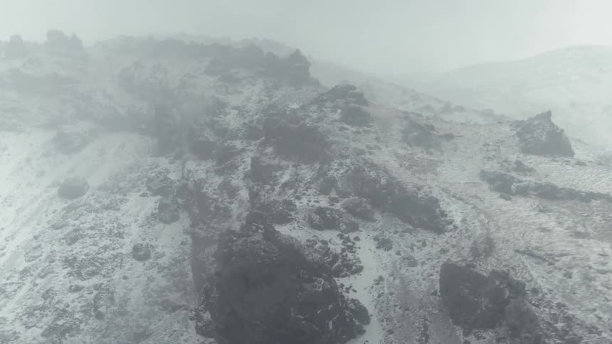 Snow falls rapidly atop a mountain