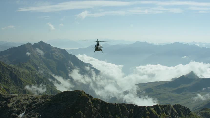 A helicopter flies above mountains