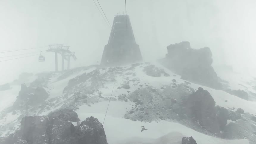 Snow falls rapidly on top of a ski slope