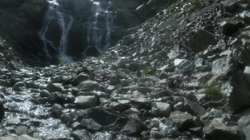 Water flows down the rocks to a stream on a sunny day