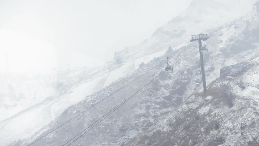 A chairlift moves down a snowy mountainside