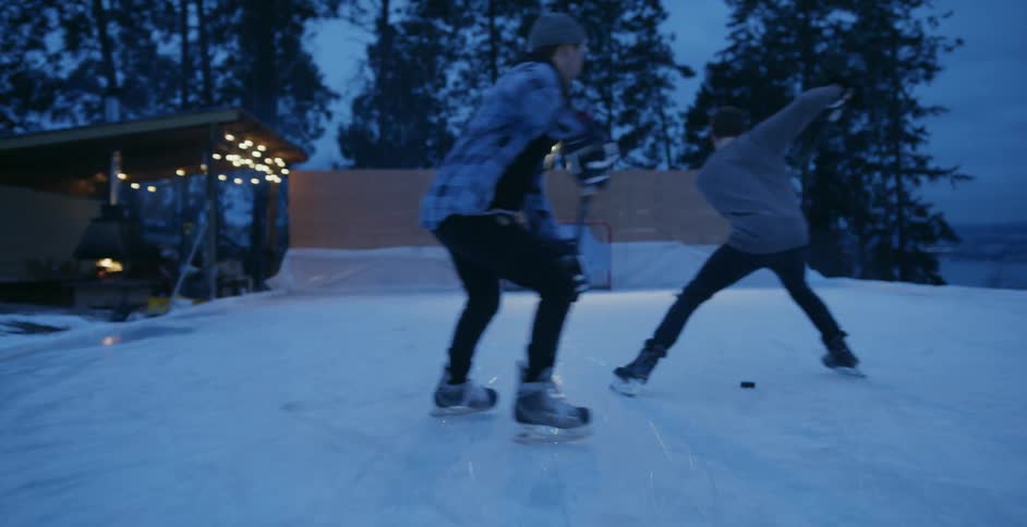 A man practices hockey on a rink outside at night
