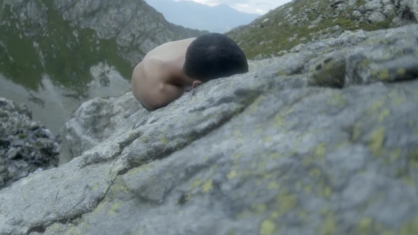 A man lays on a rock cliff