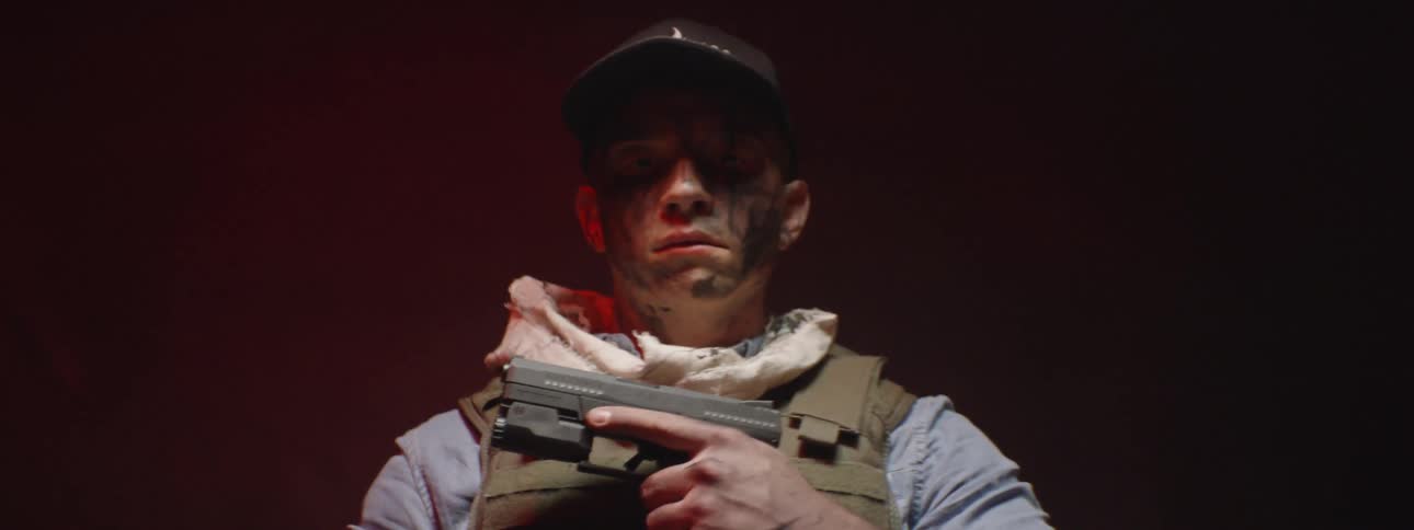 A bleeding man holds a handgun