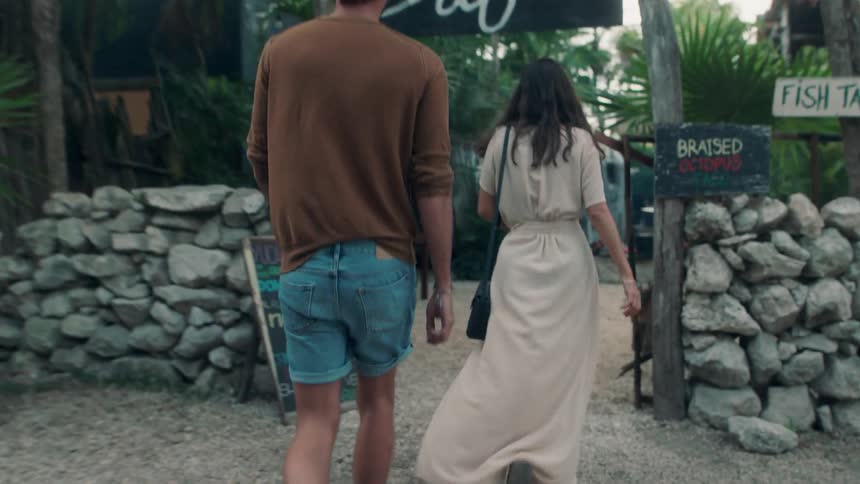 A man and woman cross a street to a restaurant