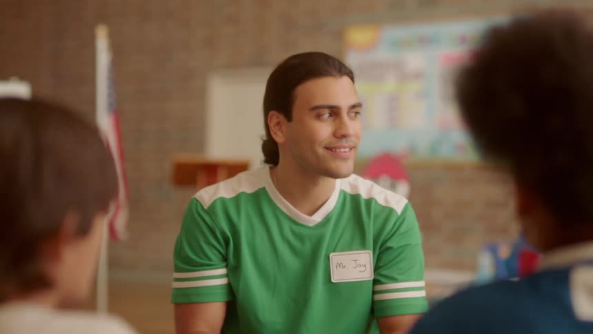 A man talks to children in a school gymnasium