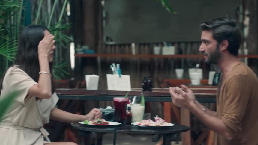 Man and woman sit outside talking and eating