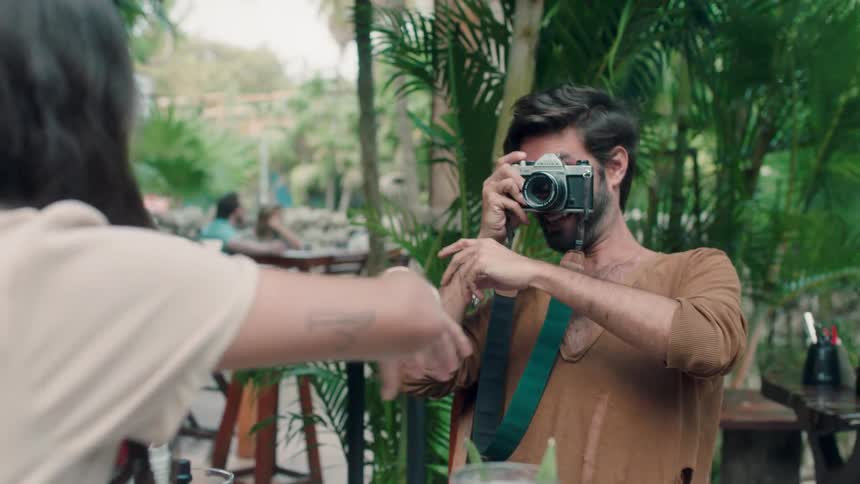 A woman is protesting as her male companion takes her picture at a restaurant table