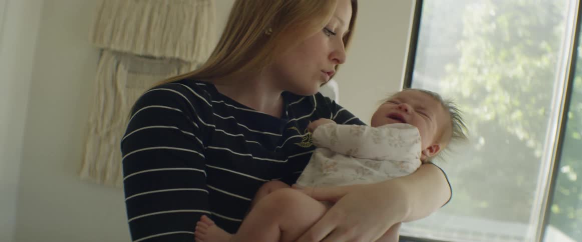 A woman rocks and sings to a newborn