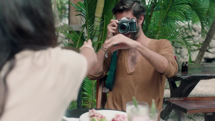 A man grabs a camera and tries to take a picture of a woman who tries to grab the camera back from him