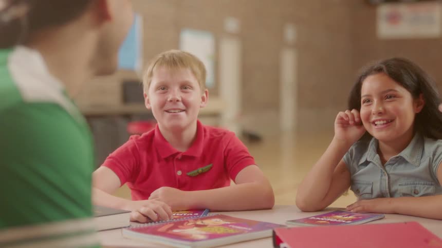 Children and adult sit and a table talking and smiling
