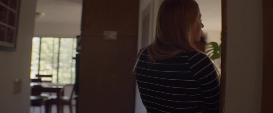 A woman is rocking a baby as she wanders through a house during the day