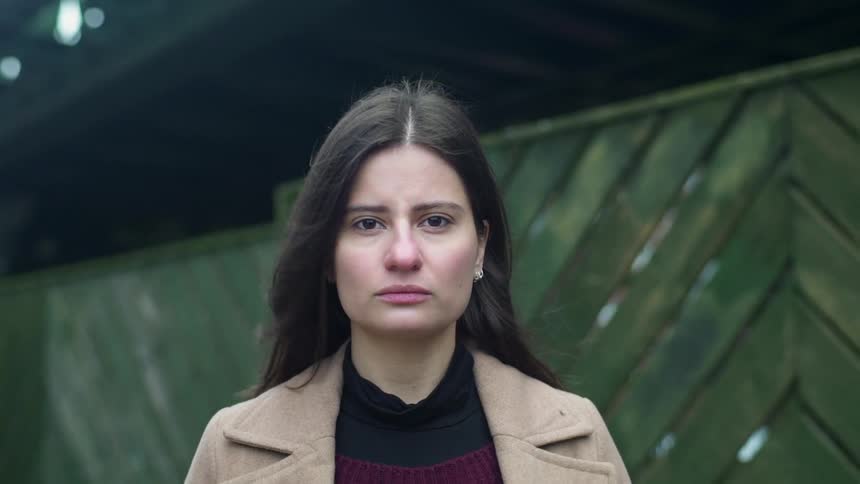 A woman frowns outside on a windy day