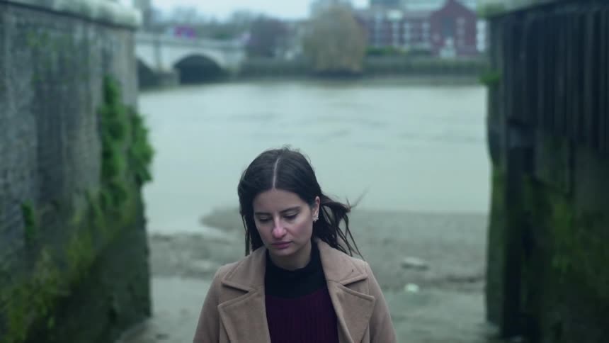 A woman stands outside on a windy day