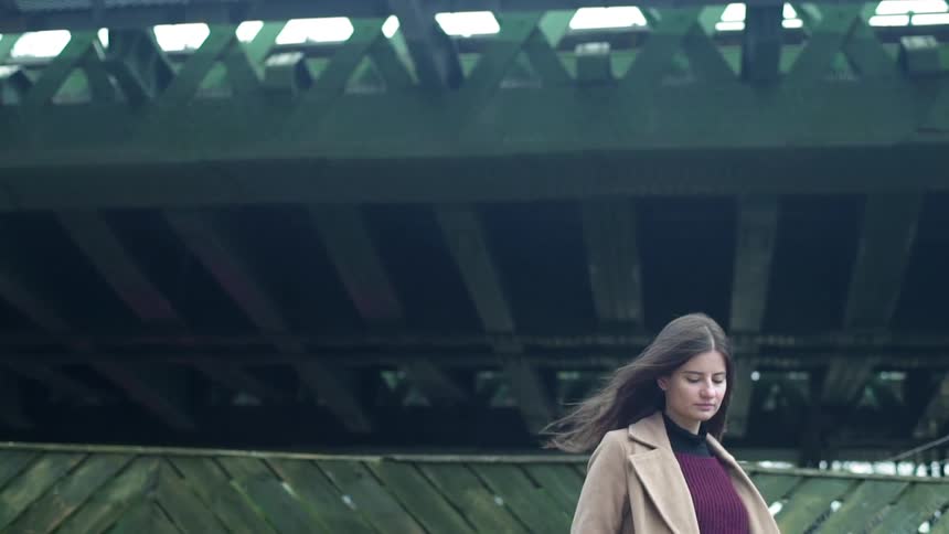 A woman stands outside on a windy day