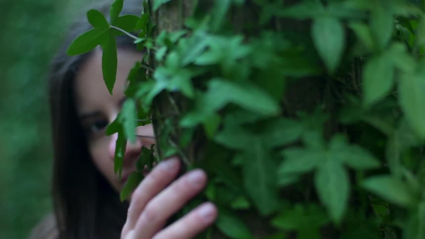 A woman touches the ivy growing on a tree