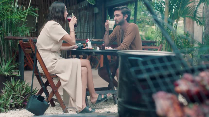 A man and woman are having drinks at an outdoor restaurant during the day