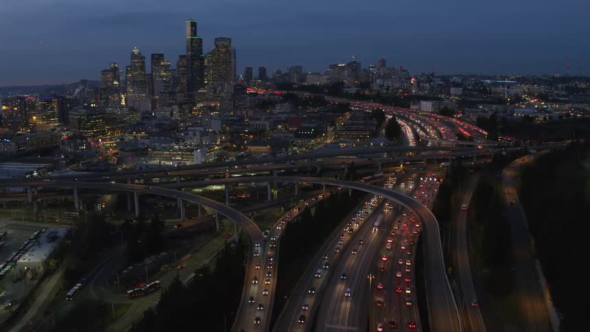 Pullback reveal of heavy traffic flowing around downtown Seattle at dusk