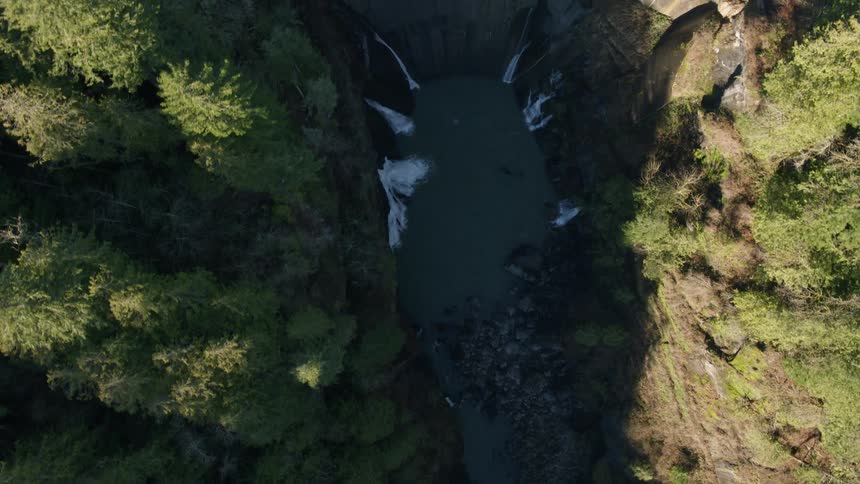 Birds eye view flying up a deep river gorge to reveal a large hydroelectric dam and reservoir
