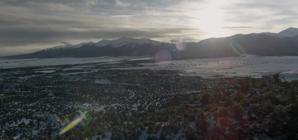 The sun shines on snow covered hills and mountain peaks
