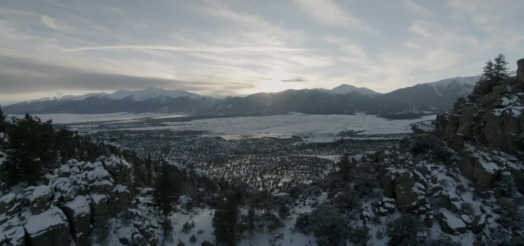 The mountain is covered with snow and trees on a cloudy day