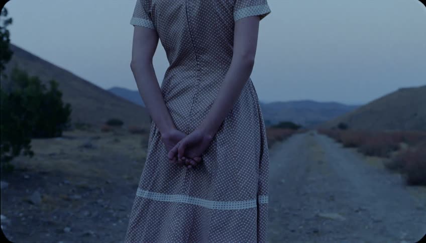 A woman walks down the trail with her arms behind her back