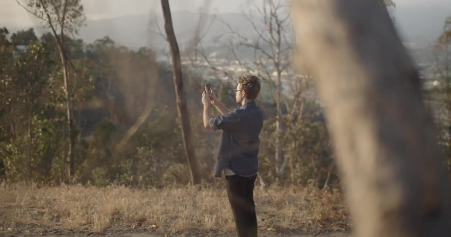 A man is pausing to take a picture outside in a natural setting in daylight