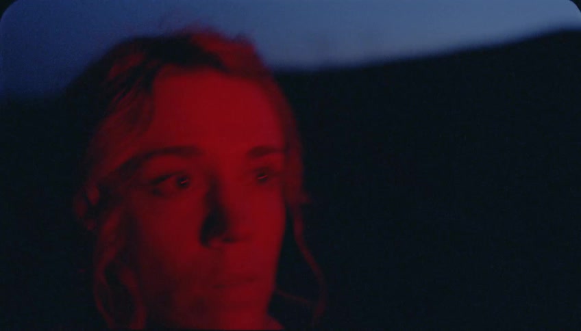 Woman walks in red flickering light at night