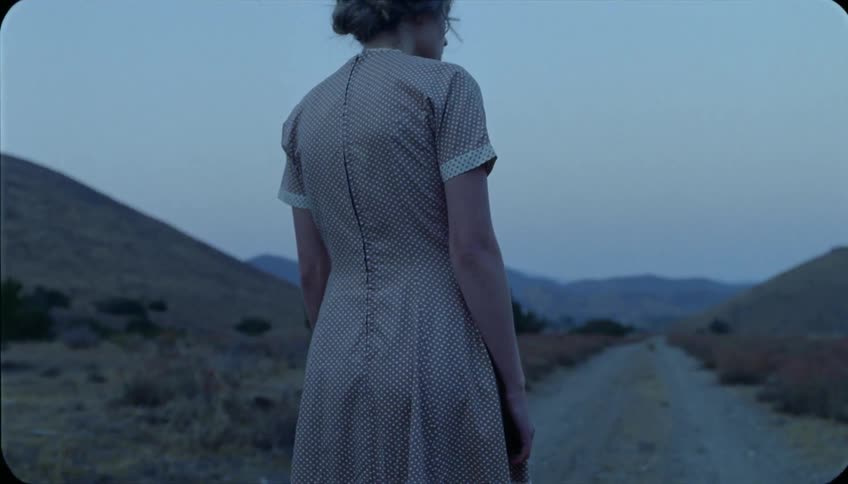 A woman walks on a rural dirt road