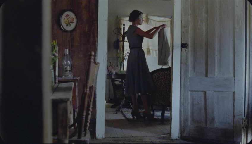 A woman places a laundry basket on a chair and folds clothes