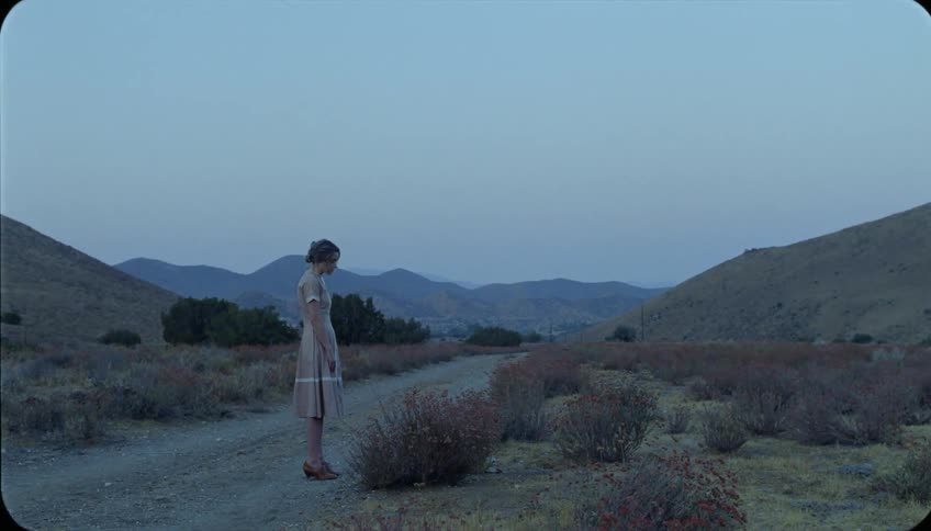 A woman stands next to the dirt trail