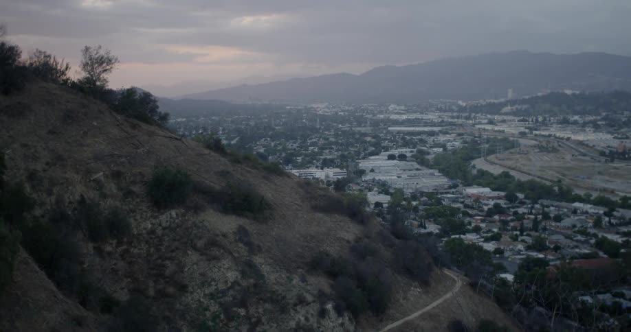 Brushy hills overlooking a city at sunset