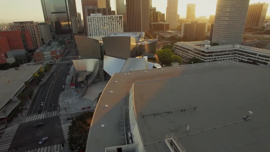The sun is streaming down on an architecturally interesting building in a city