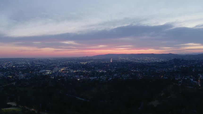 Dusk is falling over a sprawling community in a hilly area
