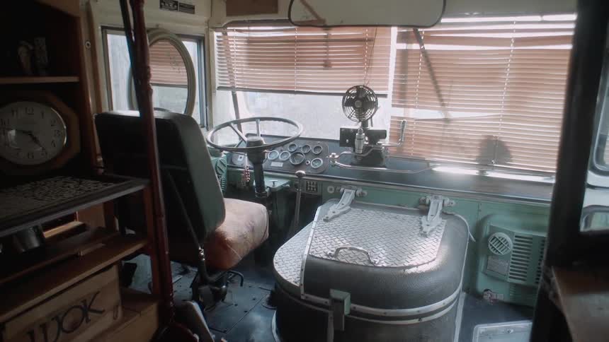 The driver's seat of an RV with blinds on the windshield