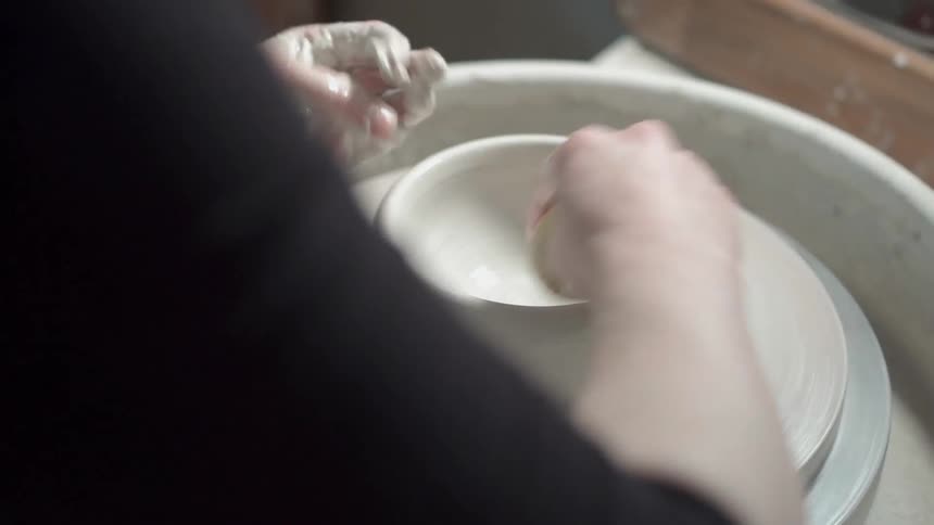 A person is making a clay bowl