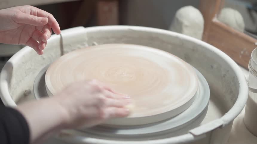 A woman works at a pottery wheel