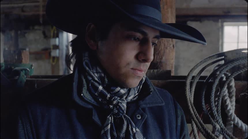 A cowboy shakes his head in a barn