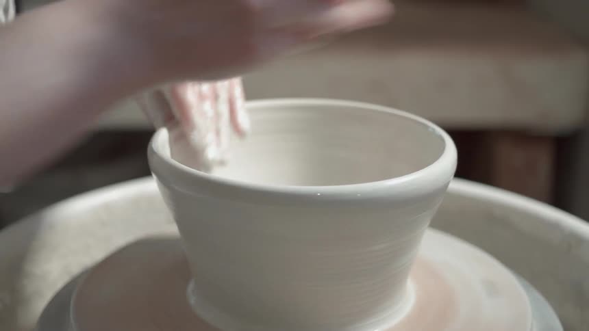 Person makes a bowl on a spinning pottery wheel