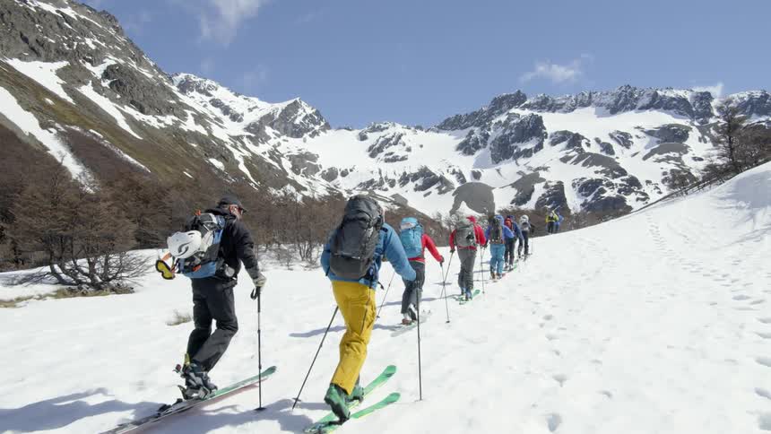 The group of people are hiking up the hill in line