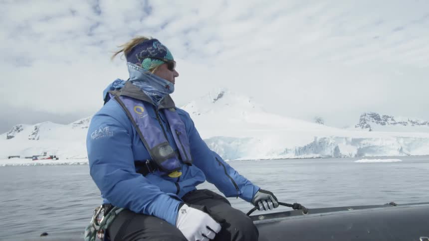 A man rides on a boat near snowy mountains