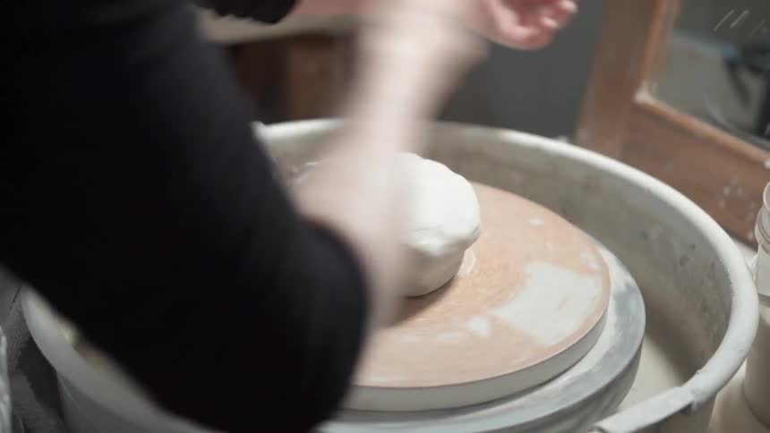 A person molding clay on a pottery wheel