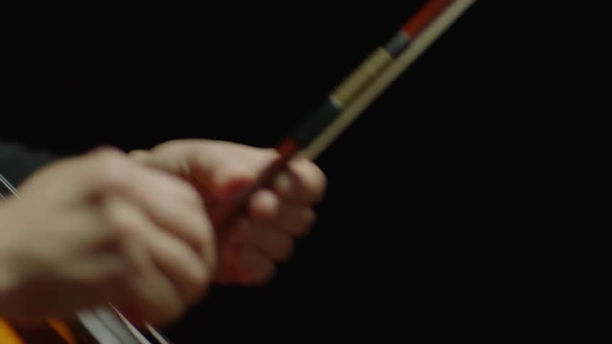A cellist adjusts their cello bow