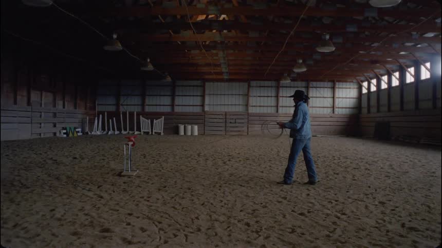 A cowboy throws a lasso inside a barn