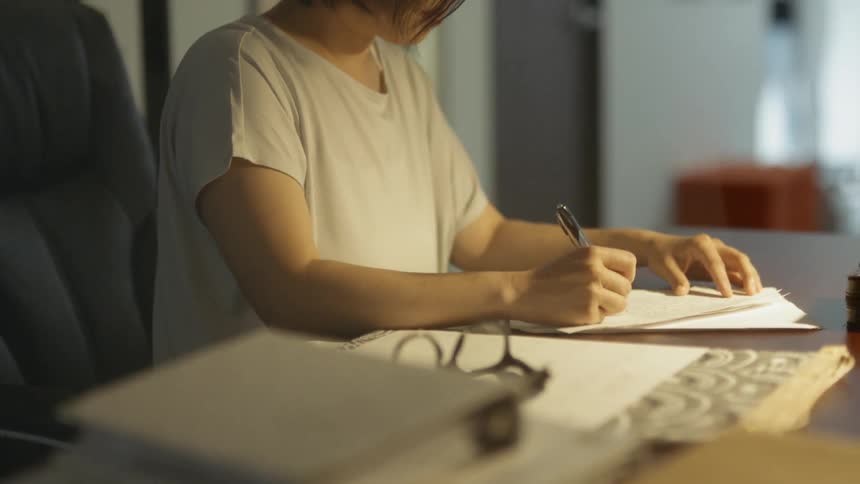 A woman sitting at a desk and writing on a paper