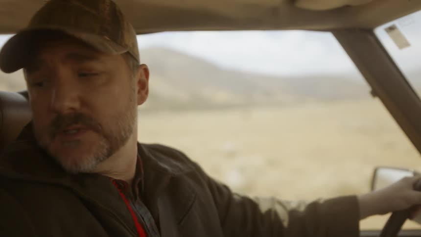 A man talks while driving on a rural road