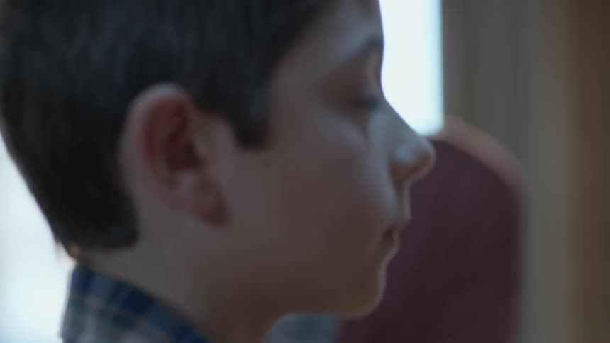 A young boy walks up to the blackboard in a classroom