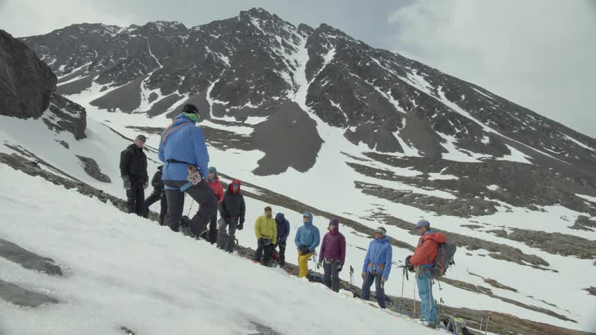 Person talks to a group of people on a snowy mountain