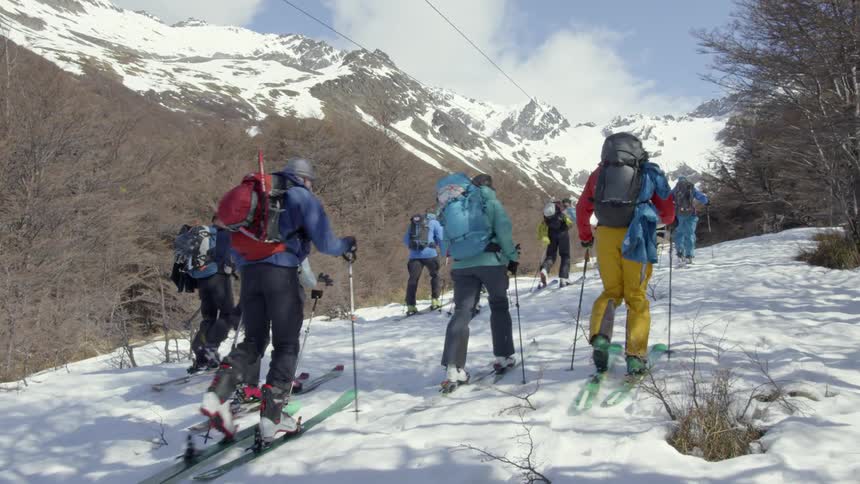 A group of people on skis travel up the slope